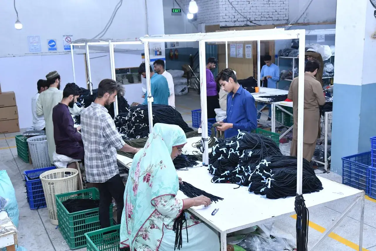 The checking floor: cord being checked by hand and tied into tagged hanks at inspection benches, with cartons stacked along the wall.
