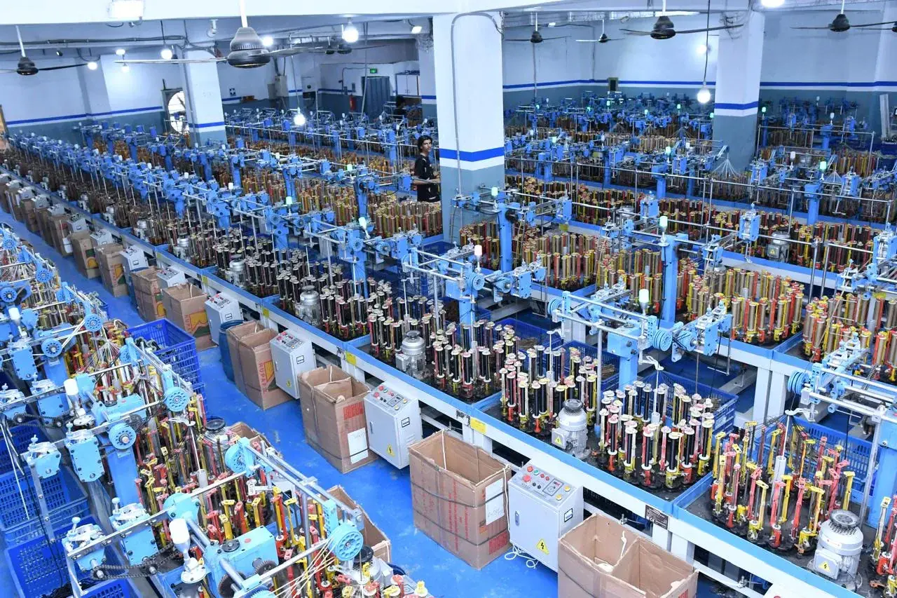 The braiding hall from above: rows of high-speed braiding machines running the length of the floor, each with its bank of bobbins.